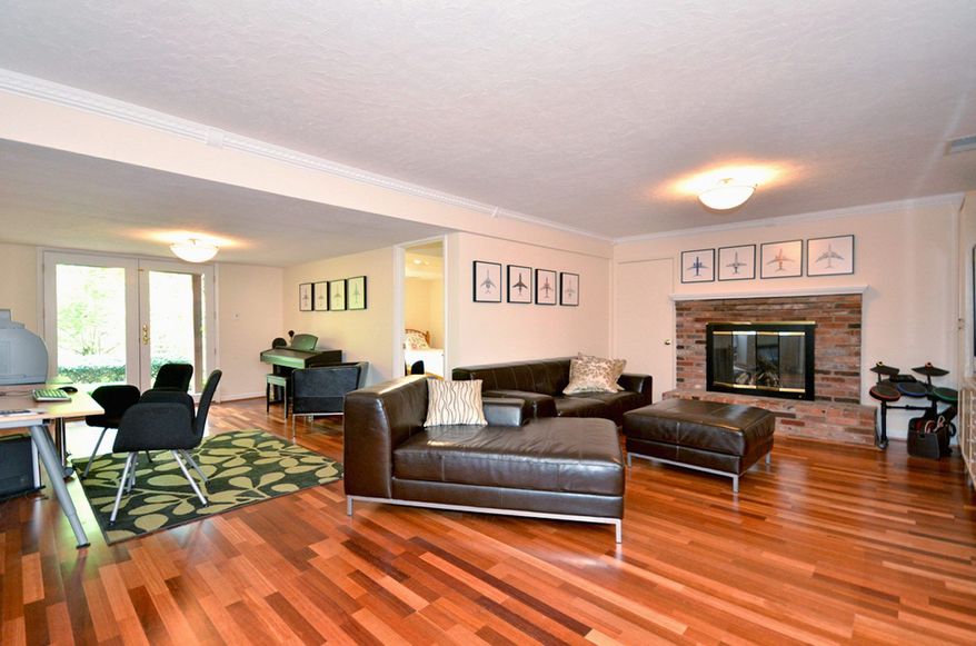 The lower-level recreation room has new flooring and a gas fireplace. French doors lead to the stone patio.
