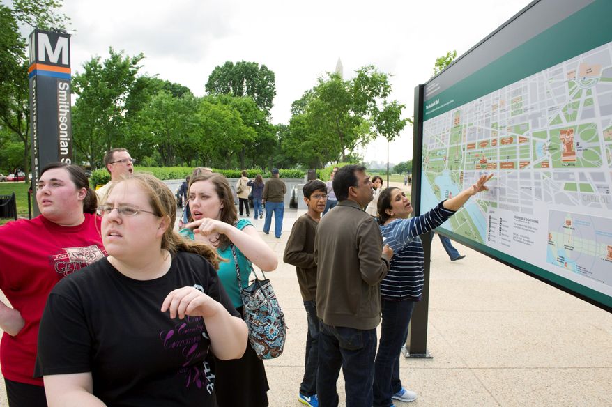 Friends (from left) Katie Devereaux, Laura Tucker and Kathryn Johnson discuss their next move at the detailed map of the Mall that made its debut Tuesday outside of the Smithsonian Metro Station. (Rod Lamkey Jr./The Washington Times)