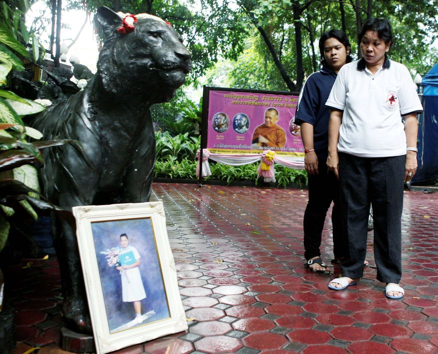 At Pathum Wanaram Temple in Bangkok last week, Payao Akkhahad and her son, Nattanakrit Akkhahad, look at a portrait of her daughter, Kamolkate, who was killed one year ago at the Buddhist temple. Kamolkate was a volunteer nurse when gunmen fired into the complex on the final day of militant anti-government demonstrations. (Associated Press)