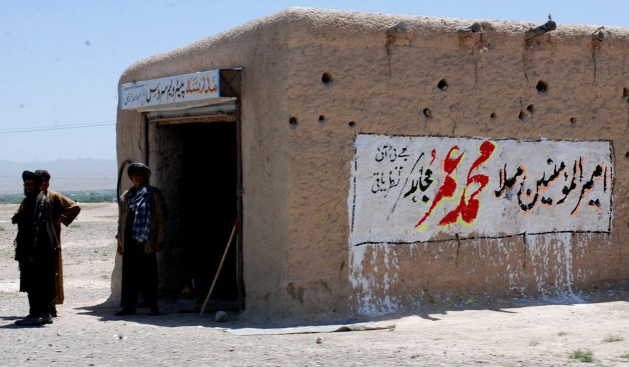 ** FILE ** Local residents stand outside a shop with graffiti reading &quot;leader of Muslims Mullah Mohammad Omar,&quot; on Sunday, May 8, 2011, in Pashin, 100 kilometers south of Quetta, Pakistan. (AP Photo/Arshad Butt)