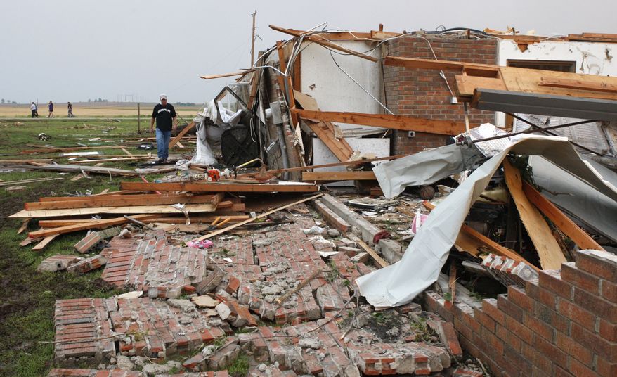 Matt McElvany walks past the home of his friend Brent Boutwell (not pictured) in Piedmont, Okla., following a tornado on Tuesday, May 24, 2011. (AP Photo/Sue Ogrocki)