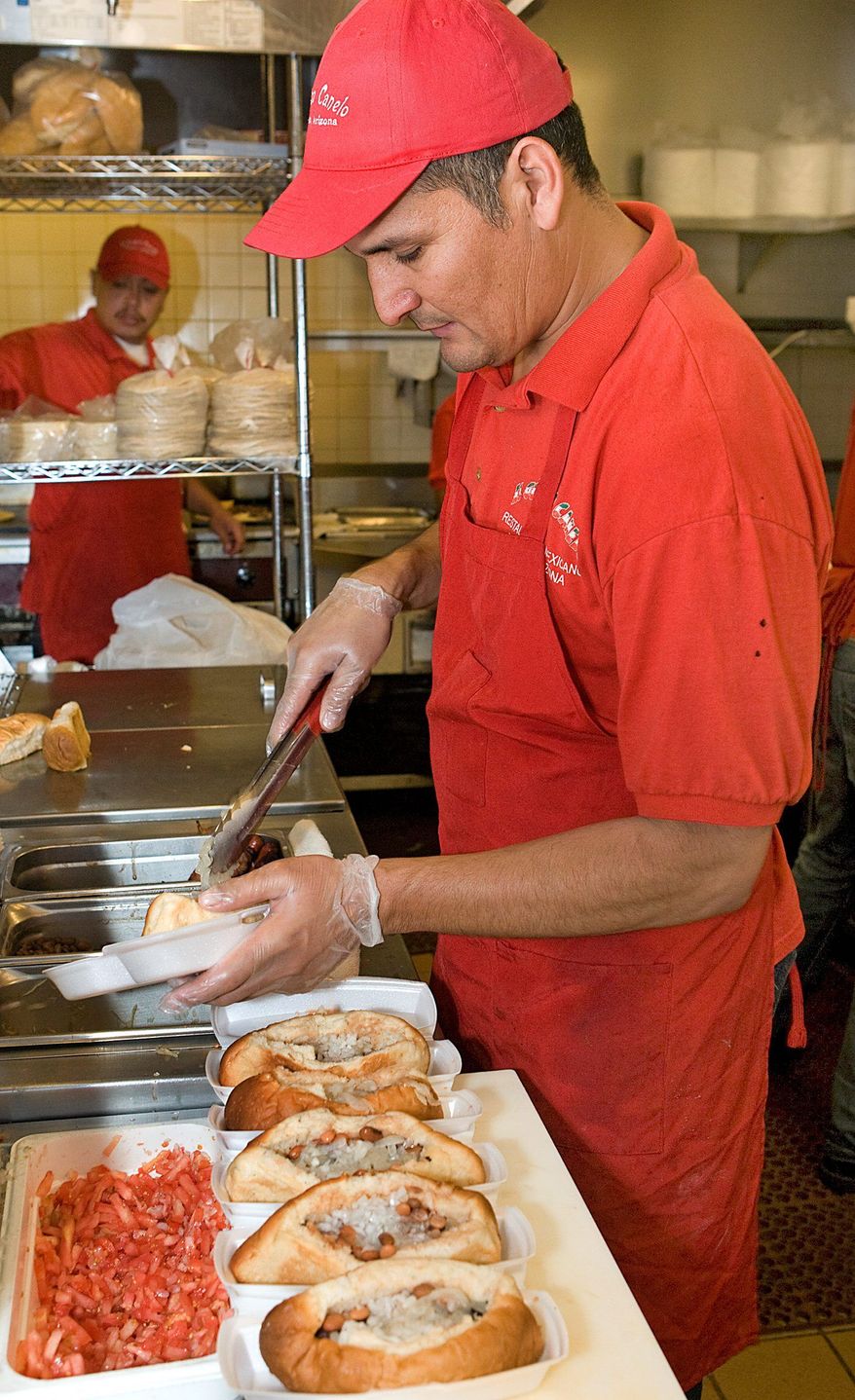 Carlos Covarrubias prepares Sonoran hot dogs for the lunch crowd at the El Guero Canelo restaurant. After the hot dog is wrapped in bacon, a healthy portion of pinto beans is dropped on top, followed by diced tomatoes, onions, mustard, mayonnaise and either jalapeno sauce or salsa. Ketchup and cheese are options, too.