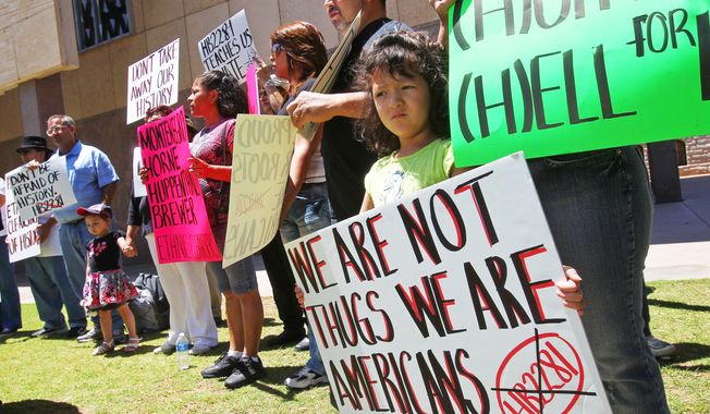 **FILE** Miroslava Acosta, 4, holds a sign during a rally at the Arizona state capital building in Phoenix on May 9, 2011, to protest Arizona&#x27;s decision to appeal to the U.S. Supreme Court a decision by a lower court that put the most controversial parts of the state&#x27;s immigration enforcement law on hold. (Associated Press)