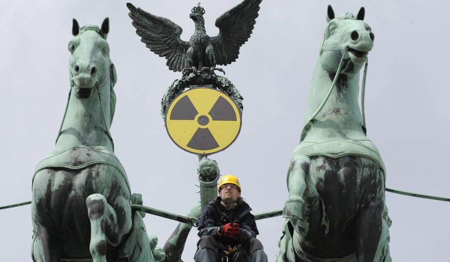 An environmental activist sits atop the Brandenburg Gate in Berlin on Sunday, May 29, 2011, after Greenpeace activists fixed a radioactive sign to the gate&#39;s Quadriga sculpture to protest the nuclear power policy of the German government. (AP Photo/dapd/Michael Gottschalk)