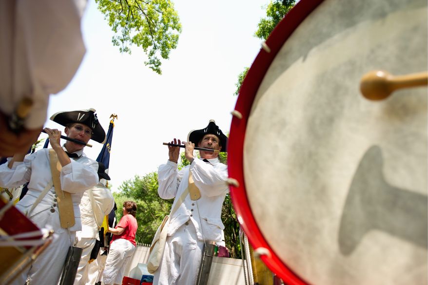 Carolyn and Ken Farley (from left) of Manassas, Va., warm up with the Fifes and Drums of Prince William III, affiliated with the National Society, Sons of the American Revolution, before the National Memorial Day Parade. (Drew Angerer/The Washington Times)