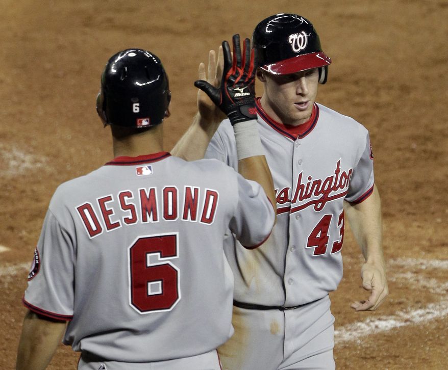 Washington Nationals' Brian Bixler (43) high fives teammate Ian Desmond (6) after scoring on an RBI triple by Roger Bernadina during the ninth inning against the Arizona Diamondbacks. The Nationals won 6-1 behind seven strong innings from Jordan Zimmermann. (AP Photo/Matt York)