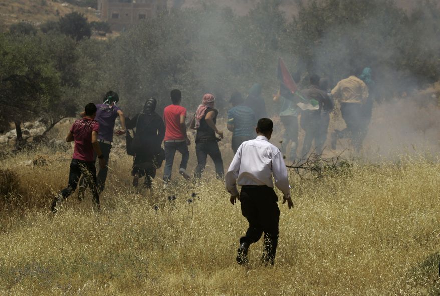 Palestinians run from tear gas fired by Israeli soldiers (not seen) during a demonstration in the West Bank village of Dir Al-hatab, near Nablus, on Sunday, June 5, 2011. The Palestinians were marking the anniversary of the Arab defeat in the 1967 Mideast war. (AP Photo/Nasser Ishtayeh)