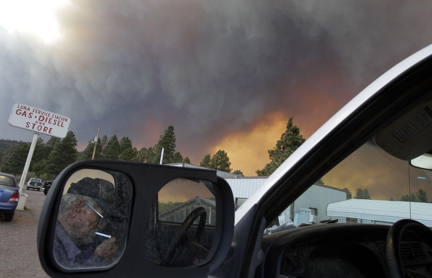 Jerry Kinney (reflected in the mirror), 73, lights a cigarette as smoke plumes from the Wallow fire fill the sky in Luna, N.M., on Monday, June 6, 2011. (AP Photo/Jae C. Hong)