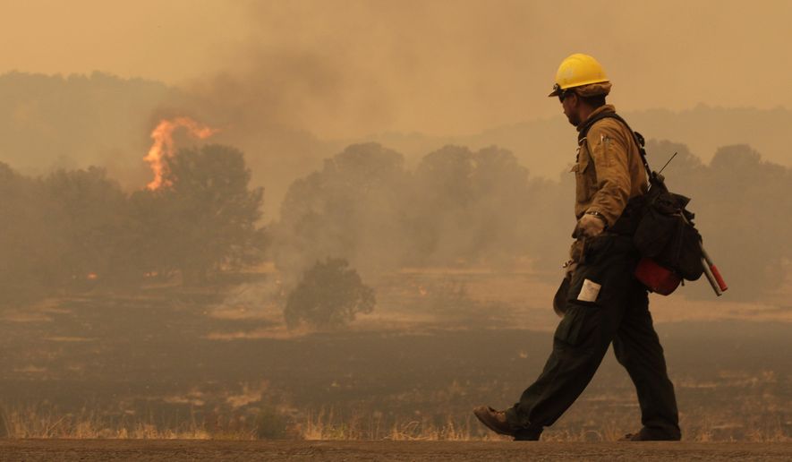 Firefighter Rigoberto Torres, of Orange Cove, Calif., walks along the road while watching a flame during the Wallow fire in the Apache-Sitgreaves National Forest near Springerville, Ariz., on June 7, 2011. (Associated Press) **FILE**