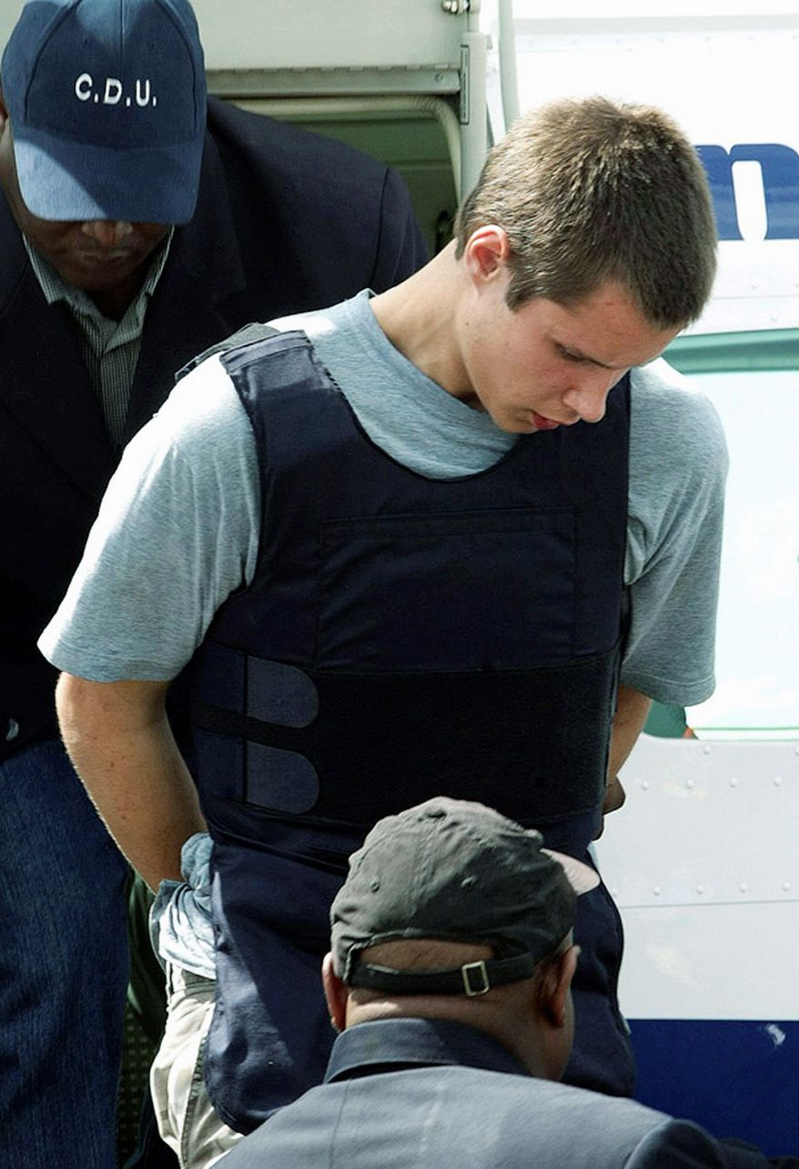 Colton Harris-Moore, seen here in July 2010, exits a plane handcuffed and escorted by police upon arrival in Nassau, Bahamas. He was subsequently extradited back to the U.S. for trial. On Thursday, he pleaded not guilty to a series of crimes. (Associated Press)