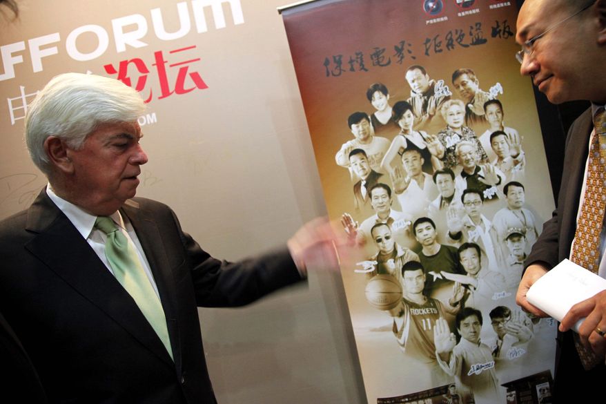 ASSOCIATED PRESS
Chris Dodd (left) looks at a Chinese poster about anti-piracy prior to a seminar as part of the 14th Shanghai International Film Festival. Mr. Dodd heads the Motion Picture Association of America.