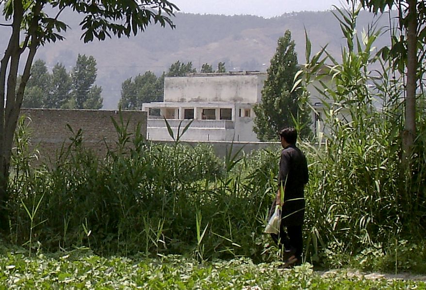 A local resident walks near a house (center) on Wednesday, June 15, 2011, where al Qaeda leader Osama bin Laden was caught and killed in Abbottabad, Pakistan, in early May. (AP Photo/Aqeel Ahmed)