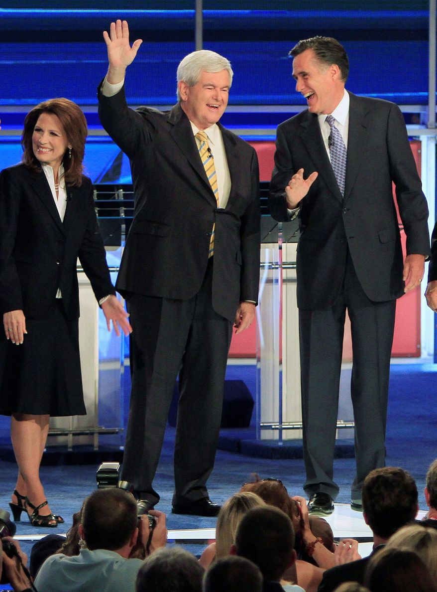 Former Massachusetts Gov. Mitt Romney (right) and former House Speaker Newt Gingrich share a laugh and acknowledge the audience before the first New Hampshire Republican presidential debate at St. Anselm College in Manchester on Monday. Rep. Michele Bachmann of Minnesota (left), officially declared her candidacy during the evening. (Associated Press)