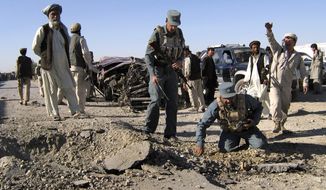 Afghan police officers inspect the site of a blast in the central province of Ghazni, Afghanistan, Saturday, June 18, 2011. Two roadside bomb attacks on Saturday killed four private security guards escorting supply convoys for a NATO base in eastern Afghanistan, a police chief said. (AP Photo/Rahmatullah Nikzad)