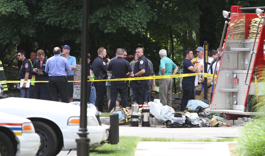 Various police and fire agencies work at the nearby wreckage site of a small plane crash, Saturday, June 18, 2011 in Armonk, N.Y.. Officials say a small plane crashed about a mile north of a suburban airport north of New York City, bursting into flames and killing three people on board. (Associated Press/The Journal News)