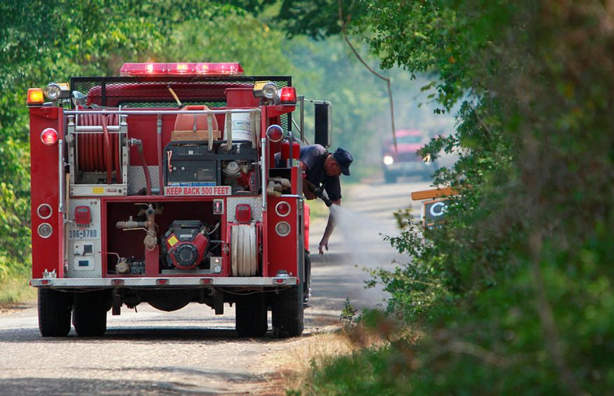 A volunteer firefighter extinguishes flares from a wildfire near Stoneham, Texas, on Monday, June 20, 2011. Several wildfires broke out from unusually hot and windy weather. (AP Photo/Houston Chronicle, Mayra Beltran)