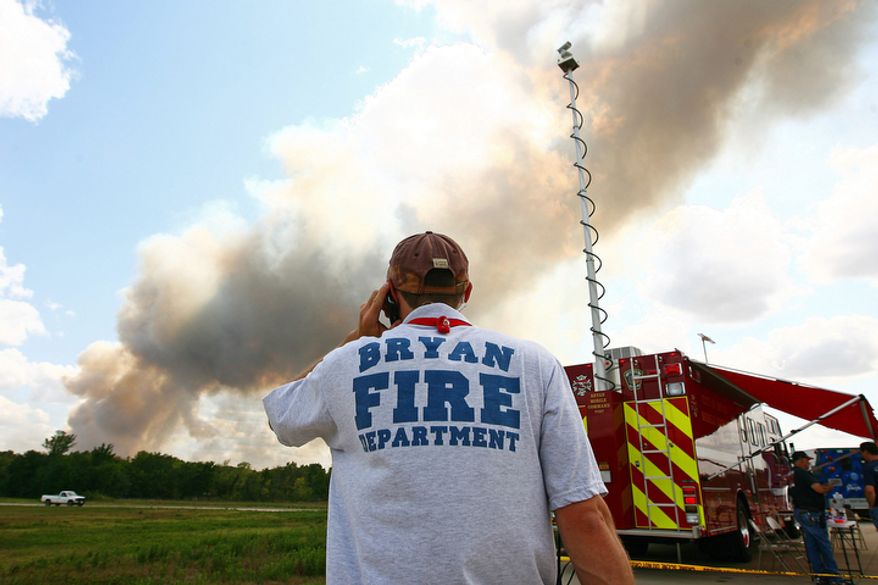 A Bryan Fire Department firefighter watches a plume of smoke rise over the City of Bryan mobile command post on in Plantersville, Texas. (AP Photo/The Courier, Karl Anderson)