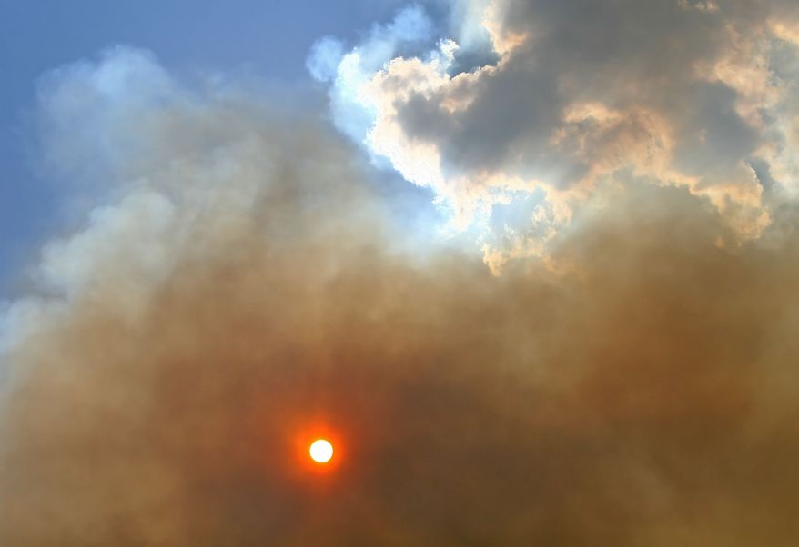 The sun shines through wildfire smoke on Monday, June 20, 2011, in Grimes County near Plantersville, Texas. (AP Photo/The Courier, Karl Anderson)