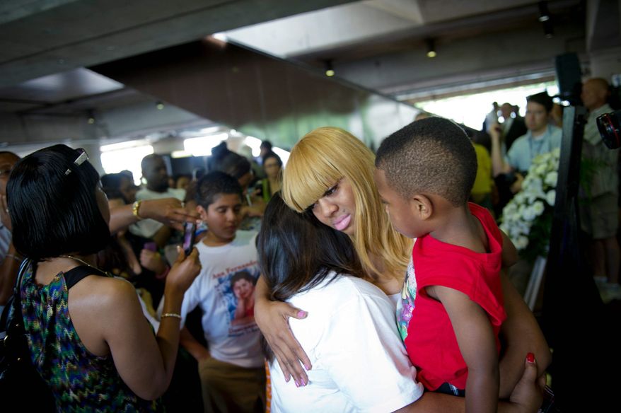 Keonda King, whose little sister Lavonda King was killed in a Metrorail crash, holds her sister's son, Emmanuel King, 7, as she hugs Evelyn Fernandez, whose mother also was killed in the crash. (Rod Lamkey Jr./The Washington Times)
