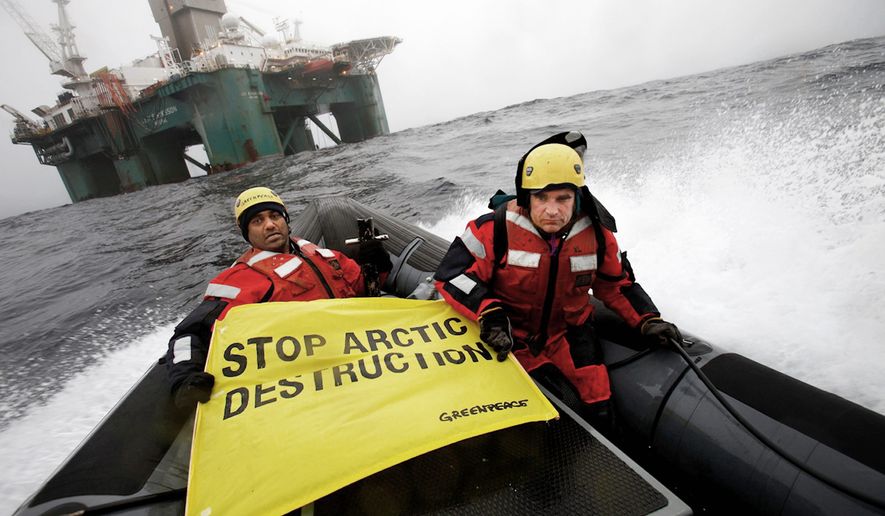 Greenpeace International global chief Kumi Naidoo (left) and an unidentified acquaintance make their view known on a boat near an oil rig in the Davis Strait, off Greenland&#39;s west coast, on Friday. Greenpeace said Mr. Naidoo was making a third attempt to stop a Scottish oil company from deep-water drilling in Arctic waters. (Associated Press)