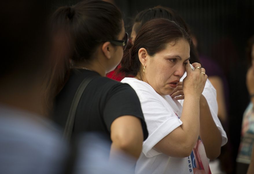 Judith Fernandez, sister of crash victim Ana Fernandez, wipes tears from her eyes as she spends time at a personal memorial to her sister and several of the other victims, on The Charles A. Langley Bridge near the Fort Totten Metro Station. (Rod Lamkey Jr./The Washington Times)