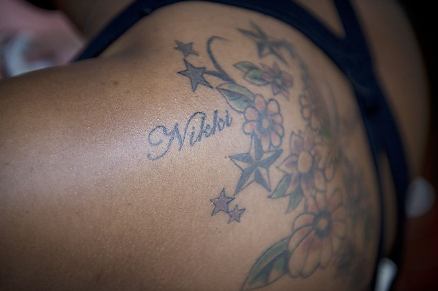 ** FILE ** Brittnae Rowe displays a tattoo in the name of her best friend Lavonda "Nikki" King, who was one of nine people killed in the June 22, 2009, Metrorail crash, during a memorial service and wreath laying ceremony at the Fort Totten Metrorail Station in Washington, D.C., on June 22, 2011. (Rod Lamkey Jr./The Washington Times)