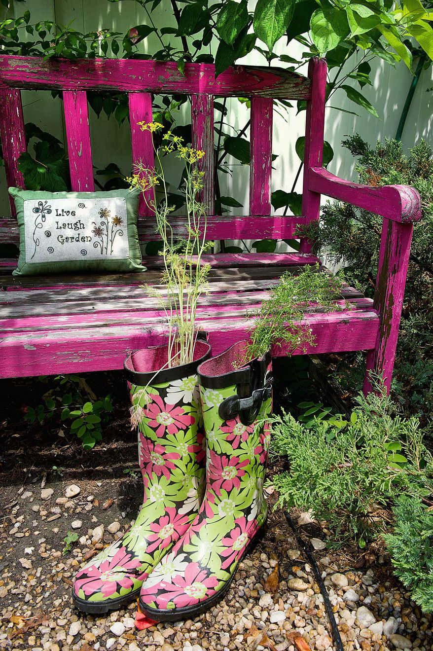 Part of making her cottage garden homier is adding touches like this bench, a pillow, and using patterned boots as a planter for Silver Spring, Md., gardener Kathy Jentz, who is also editor of Washington Gardener magazine. This image was made Monday, June 20, 2011. (Barbara L. Salisbury/The Washington Times)