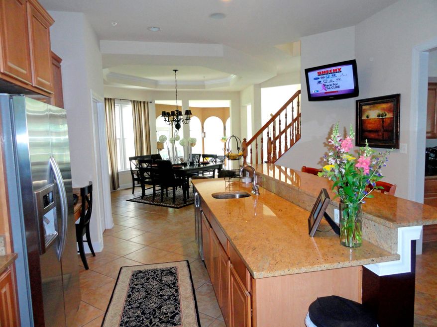 An extra-long granite breakfast bar in the kitchen offers an additional place to dine. On the opposite side is a food prep area with a sink.