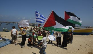Palestinian children hold Palestinian flags and a blue-and-white Greek flag as they demonstrate in support of the Gaza-bound flotilla in the port of Gaza City, Gaza Strip, on Sunday, July 3, 2011. (AP Photo/Hatem Moussa)