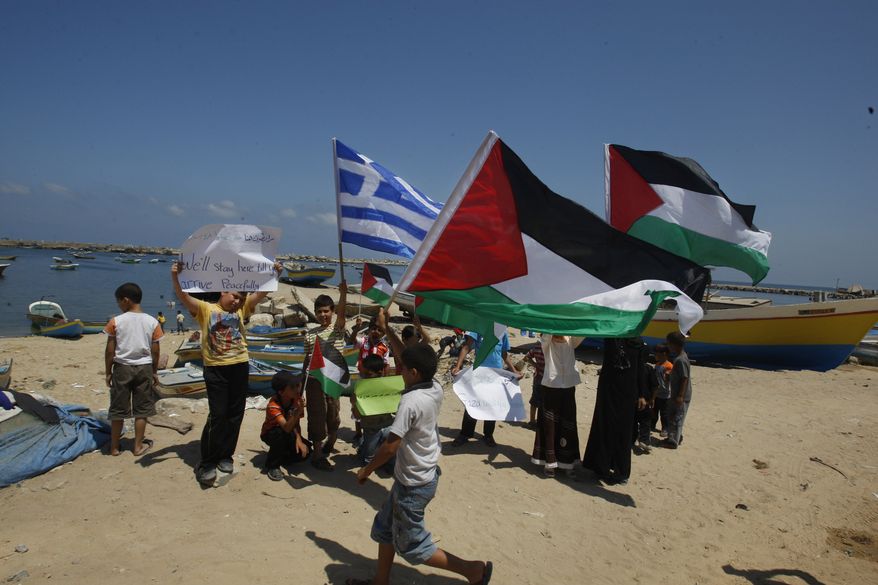 Palestinian children hold Palestinian flags and a blue-and-white Greek flag as they demonstrate in support of the Gaza-bound flotilla in the port of Gaza City, Gaza Strip, on Sunday, July 3, 2011. (AP Photo/Hatem Moussa)
