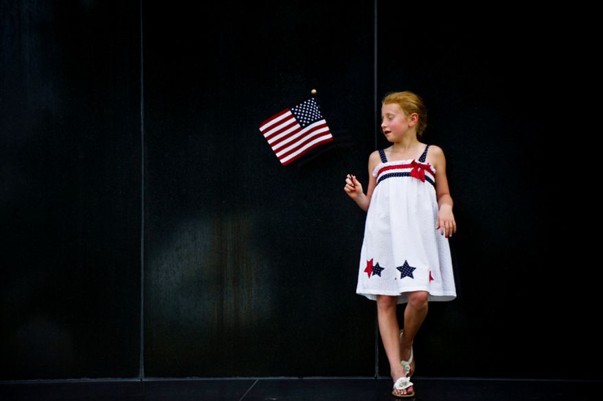 Anne Byrd Fickling, 7, of Fredericksburg, Va., holds an American flag at the base of the Iwo Jima Memorial in Arlington, Va., as she waits for the fireworks to start on Monday, July 4, 2011. (Drew Angerer/The Washington Times)
