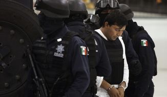 Mexican Federal Police agents escort Jesus Enrique Rejon Aguilar, alias &quot;El Mamito,&quot; to his presentation to the media in Mexico City on Monday, July 4, 2011. Police believe he is connected with the killing of a U.S. Immigration and Customs Enforcement agent in February. (AP Photo/Alexandre Meneghini)
