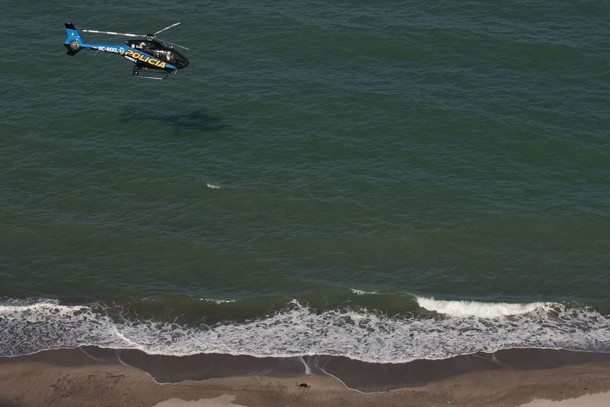 A Mexican police helicopter searches the waters of the Gulf of California for survivors of a capsized fishing boat near San Felipe, Mexico, on Monday, July 4, 2011. A U.S. tourist died after the fishing boat capsized Sunday in an unexpected storm, and seven Americans still are missing. (AP Photo/Francisco Vega)