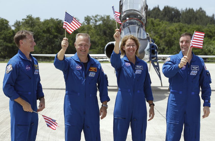 Astronaut Chris Ferguson (left), commander of the last space shuttle mission, looks on as his fellow crew members, (from left) pilot Doug Hurley and mission specialists Sandy Magnus and Rex Walheim, wave American flags after arriving at the Kennedy Space Center in Cape Canaveral, Fla., on Monday, July 4, 2011. The space shuttle Atlantis is scheduled to lift off Friday morning on a 12-day mission to the International Space Station. (AP Photo/Chris O'Meara)