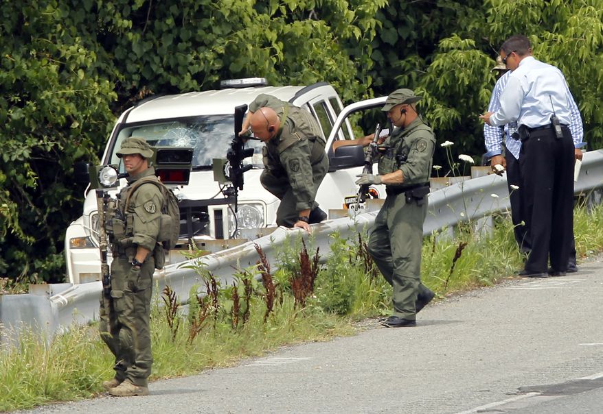 Law enforcement officials prepare to search the woods near a contractor's vehicle on Baltimore-Washington Parkway in Linthicum, Md., on July 6, 2011. Maryland State Police and Anne Arundel County police are searching for an armed man along the parkway who hit the windshield of a contractor's vehicle with a hammer before fleeing. (Associated Press)