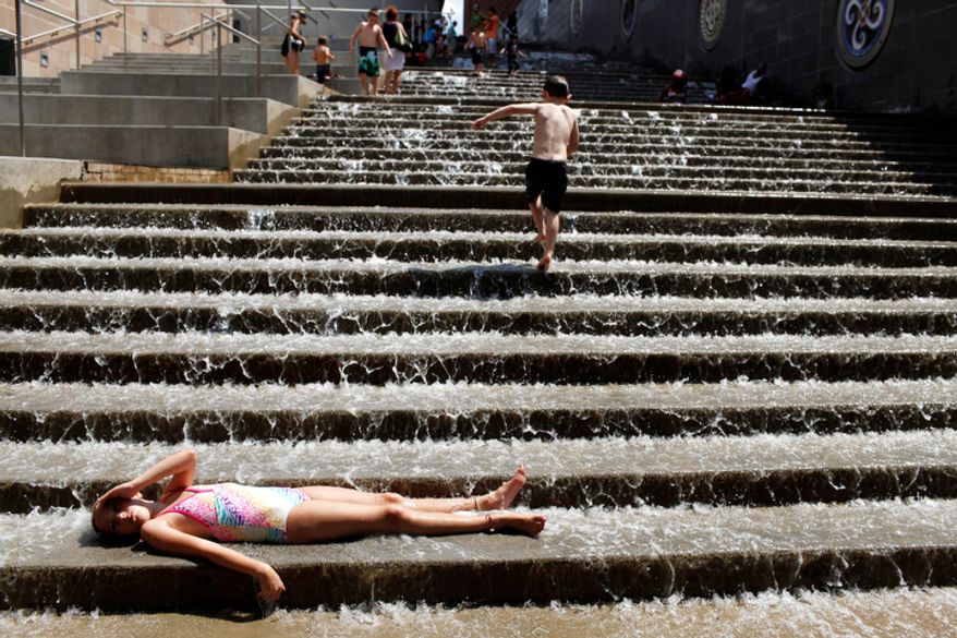 Madison Hawkins, 8, enjoys the cool water and hot sun on Monday, July 11, 2011 as she lays on the steps of The Passage in Chattanooga, Tenn. (AP Photo/Chattanooga Times Free Press, Alex Washburn)