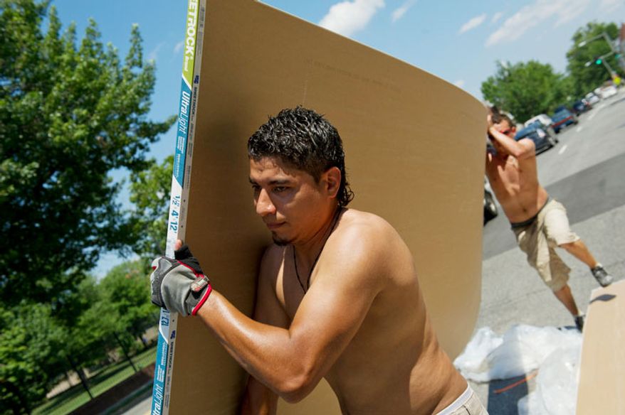 As the temperatures neared 100 degrees today, Edwardo Ramos (left) and Robert Velasquez join other men loading sheet rock into a home at 831 Florida Avenue NE in Washington, D.C., Tuesday, July 12, 2011. (Rod Lamkey Jr/The Washington Times)