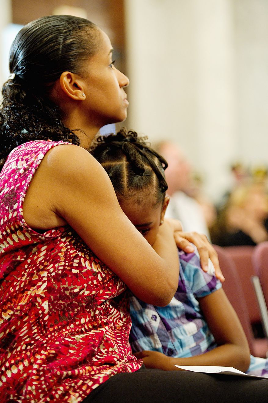 Miriam Carter of Ocoee, Fla., comforts her 6-year-old daughter, Liana, during the National 9/11 Flag stitching ceremony Thursday on Capitol Hill. Ms. Carter's sister, Maria Ramirez, was killed in the Sept. 11, 2001, attack in New York City. (Barbara L. Salisbury/The Washington Times)