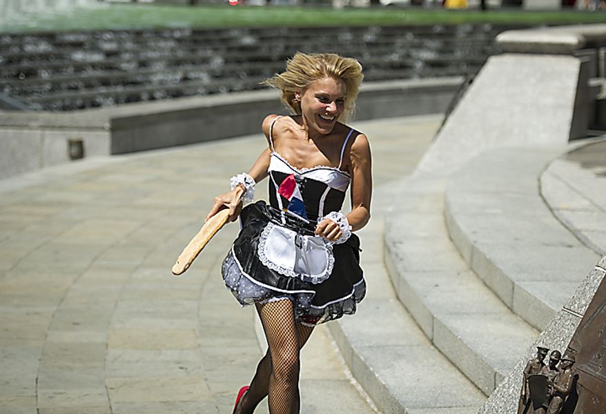 Dressed in a French maid outfit, Wendy Gordon, holding a baguette, makes her way around the United States Navy Memorial in the Baguette Relay Races, to honor Bastille Day in Washington, D.C., Thursday, July 14, 2011. The races were sponsored by Paul Bakery. (Rod Lamkey Jr/The Washington Times)