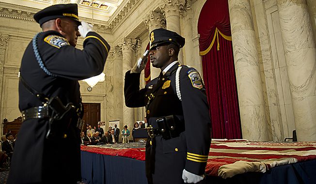 ** FILE ** Two U.S. Capitol Police officers exchange salutes as they change command while guarding the official 9/11 National flag during a stitching ceremony in the Kennedy Caucus Room in the Russell Senate Office Building in Washington, D.C., on Thursday, July 14, 2011. An American flag that was flying just south of the World Trade Center in New York City on Sept. 11, 2001, is making its way around the country and being stitched back together. (Barbara L. Salisbury/The Washington Times)