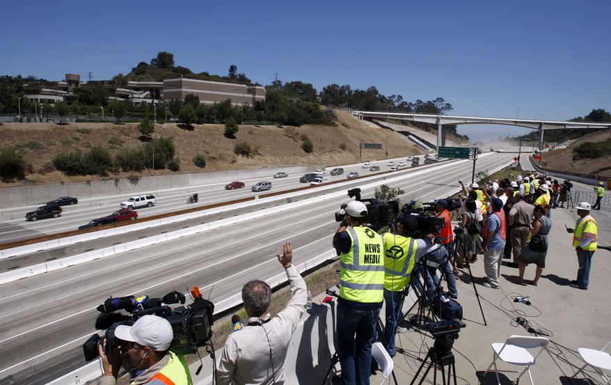 Construction officials and media get a view July 17, 2011, of the first vehicles on southbound Interstate 405 as they approach the Mulholland Drive bridge (in foreground) as demolition of a portion of the bridge is completed before noon in Los Angeles. (Associated Press/Los Angeles Times)