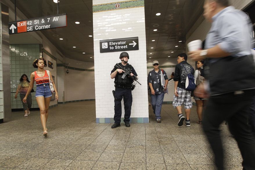 A heavily armed police officer stands guard at a Times Square subway station in New York on July 1, 2011. (Associated Press)