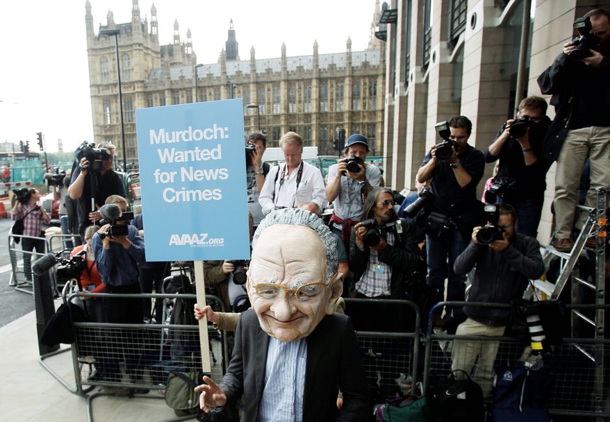 A protester wearing a Rupert Murdoch mask makes his point outside Parliament in London on Tuesday. Mr. Murdoch, CEO of News Corp., and his son James, also a company executive, were questioned for three hours by a parliamentary committee about the ongoing phone-hacking scandal in Britain. (Associated Press)