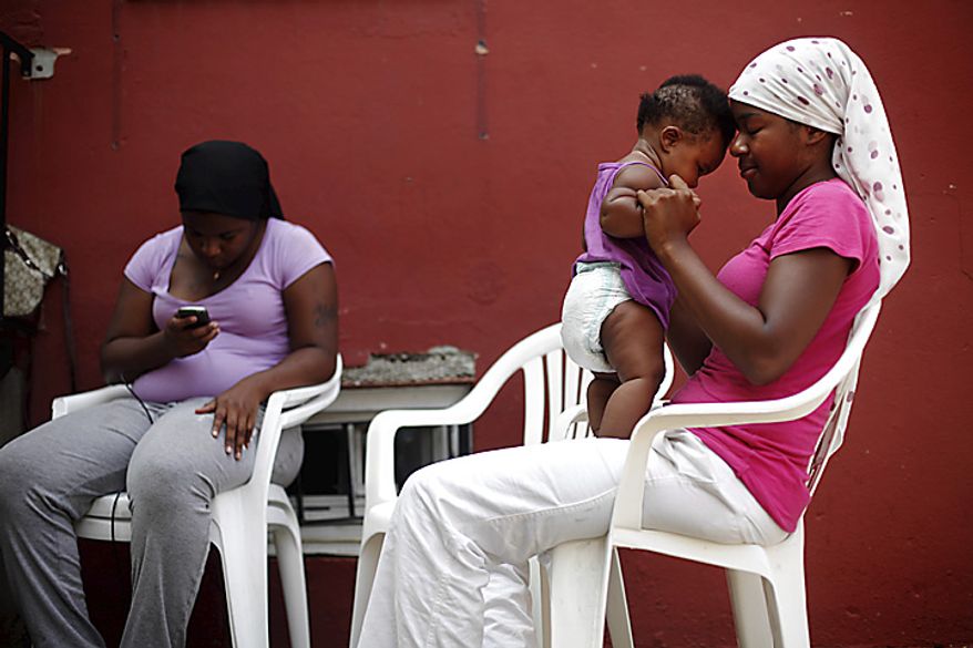 Sitting in the shade of their home Shalanda Holt, right, plays with her daughter six-month-old Siani, as her sister Yolanda Holt reads on her mobile phone Thursday, July 21, 2011, in Philadelphia. The National Weather Service says temperatures are expected to be near triple digits Thursday in Philadelphia, with a high of 96 degrees forecast for Pittsburgh. (AP Photo/Matt Rourke)