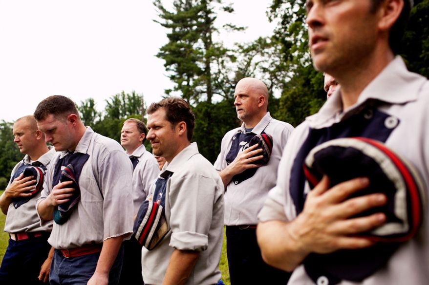 The Elkton Eclipse team, based out of Elkton, Md, hold their hats over their hearts during the National Anthem before the game. Unlike today's game, the umpire instructed fans and players to all sing in unison, instead of just one person singing at the start. (Drew Angerer/The Washington Times)