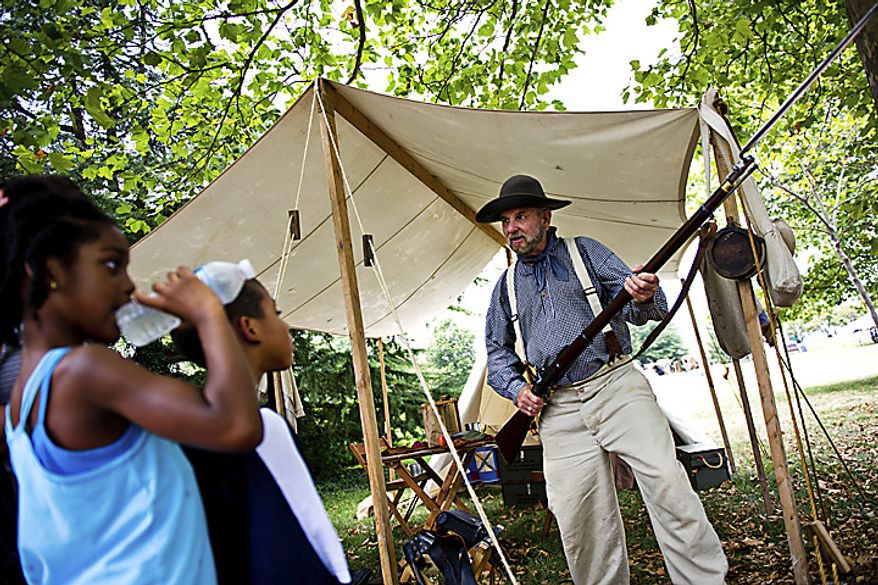 Tommy Phillips, right, of Cookeville, Tenn., talks to Leila Reynolds, 7, and Malachi Reynolds, 5, both of Fairfax, Va., at an encampment near the Manassas Museum, in Manassas, Va., Thursday, July 21, 2011. "I just love talking to people about all this history," said Phillips, who was showing off his 1853 Enfield Gun to the kids. "That's what it's all about." (Drew Angerer/The Washington Times)