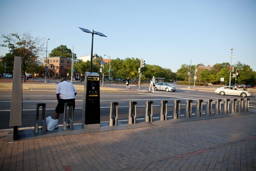 A man sits at an empty Capital Bikeshare stand near the Eastern Market Metro station in Southeast. Riders can check a station's status on a free GPS-enabled mobile application or Bikeshare's website. (Pratik Shah/The Washington Times)