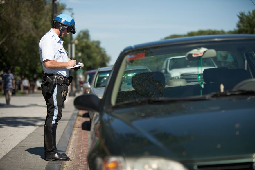 A police officer writes a parking ticket for a car illegally parked during rush hour on Constitution Avenue and west of 15th Street in Northwest Washington on Wednesday. The city is temporarily allowing people hit with citations before Jan. 1, 2010, to pay the original fines without late fees. (Pratik Shah/The Washington Times)