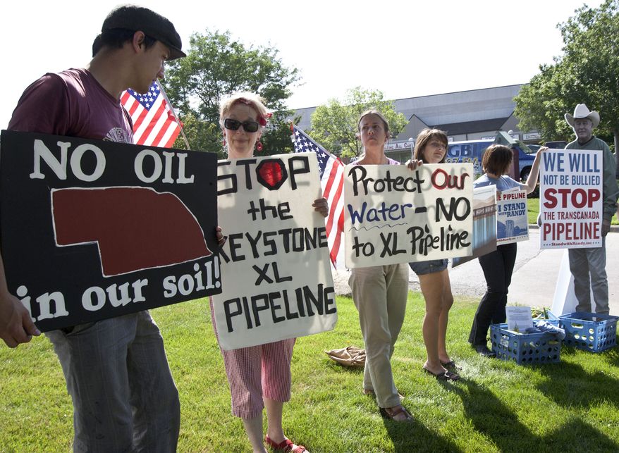 **FILE** Protesters opposed to the Keystone XL pipeline hold signs outside the office of Rep. Lee Terry, Nebraska Republican, in Omaha, Neb., on July 26, 2011. (Associated Press)