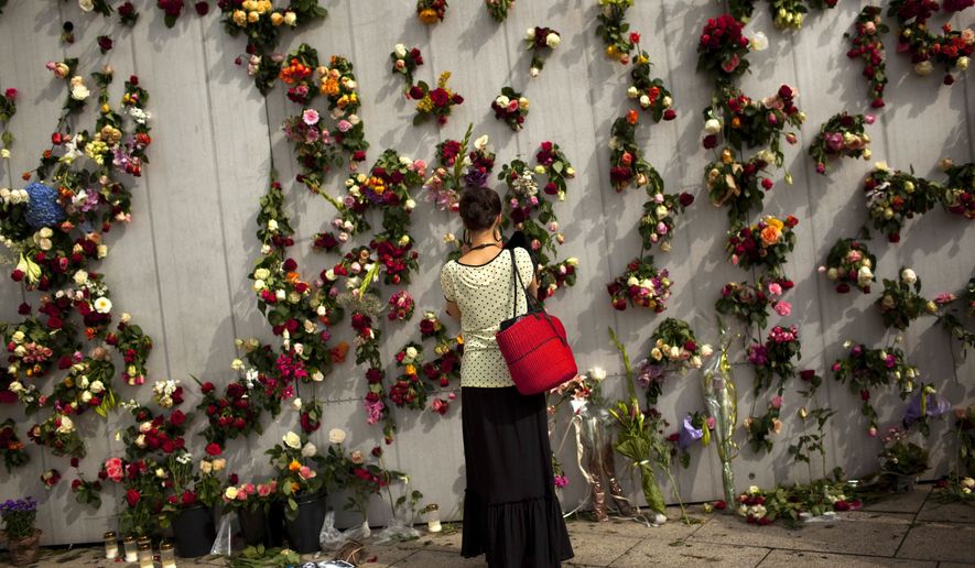 A woman is seen in front of wall decorated with flowers in memory of the victims of Friday&#39;s bomb attack and shooting rampage in Oslo, Norway, Tuesday, July 26, 2011. (AP Photo/Emilio Morenatti)